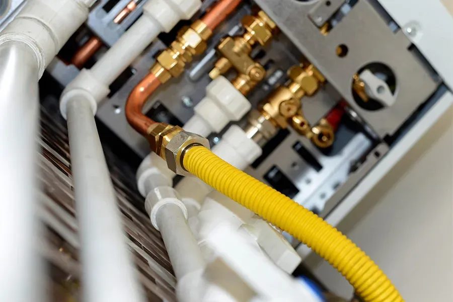 Close-up of a yellow corrugated hose connected to a brass fitting inside a mechanical panel area.